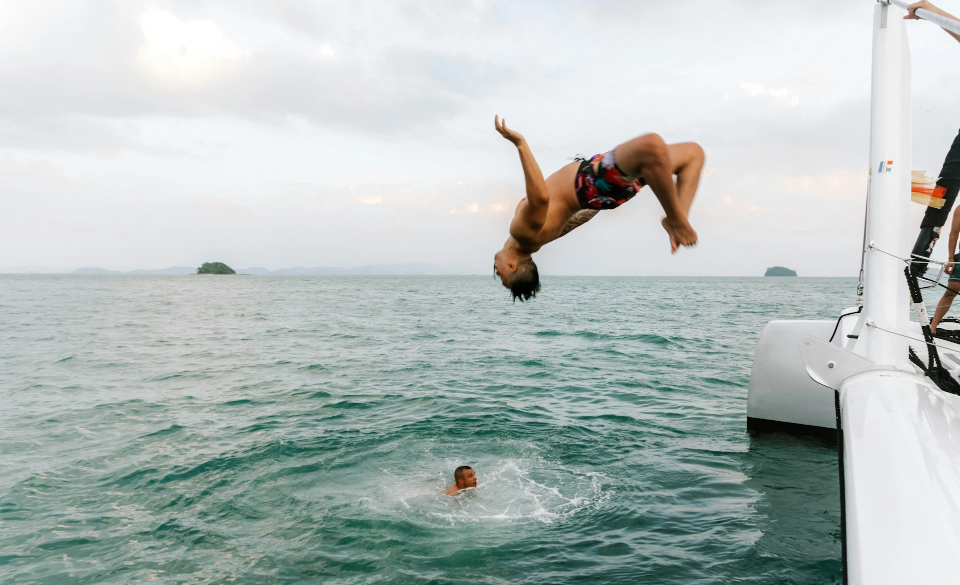 Man performing a backflip from a boat into water
